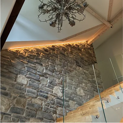 Natursteinwand im Treppenhaus mit indirekter Beleuchtung